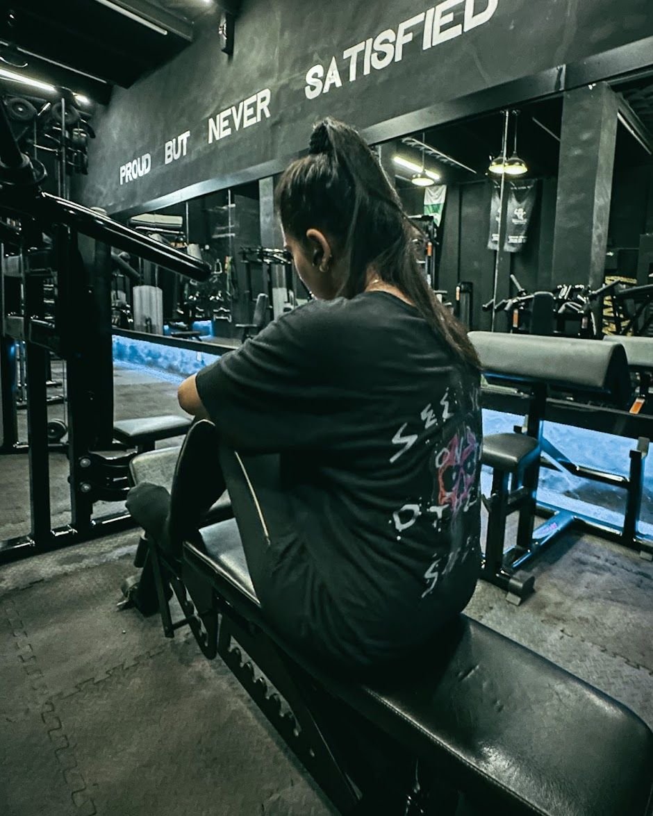Member resting on a bench under the Proud But Never Satisfied wall